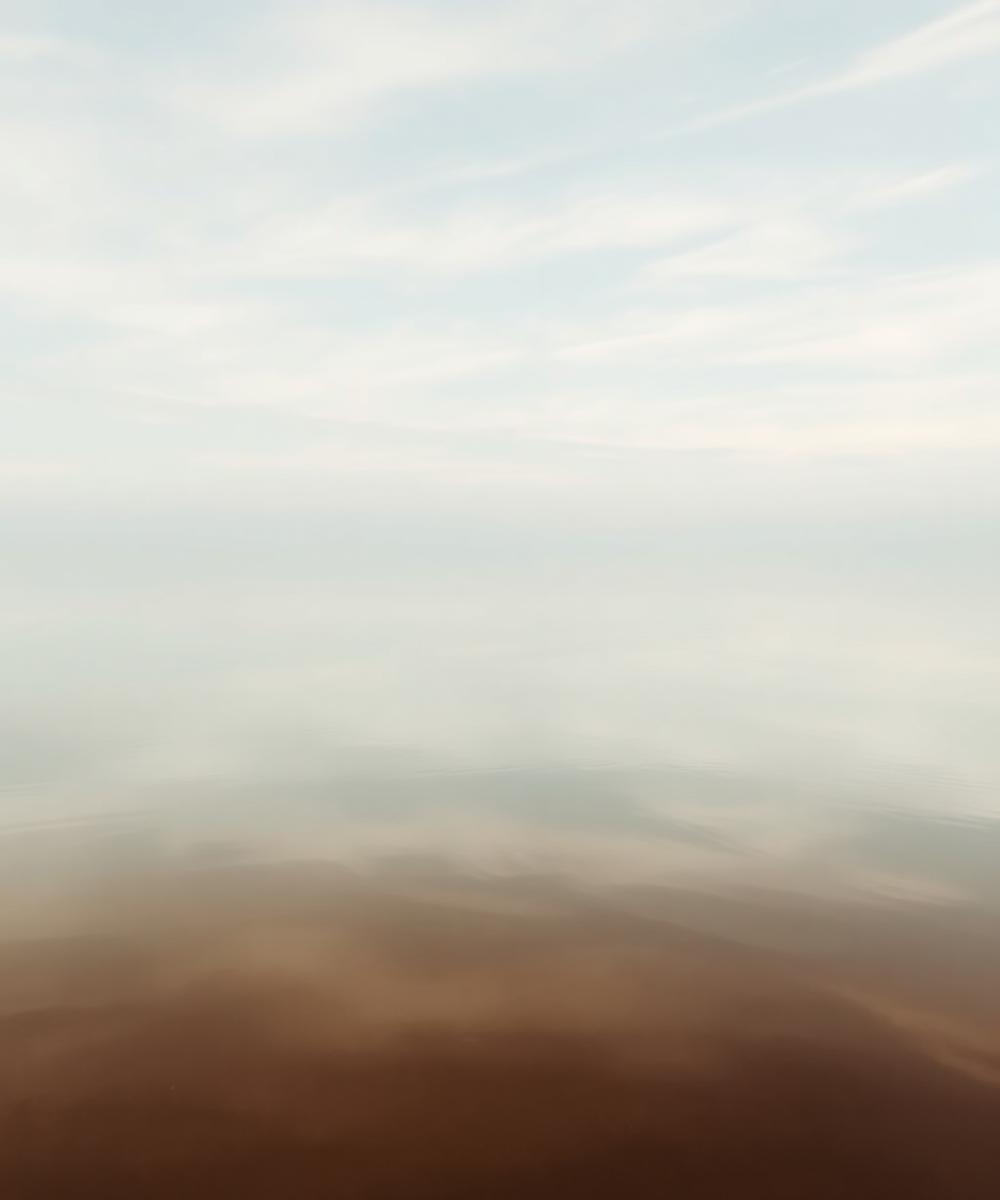 Still water reflecting an open pale sky